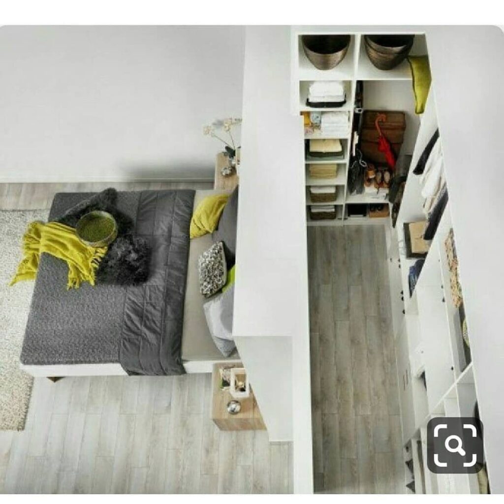 Modern bedroom with a grey bed and a white open-shelving closet system.