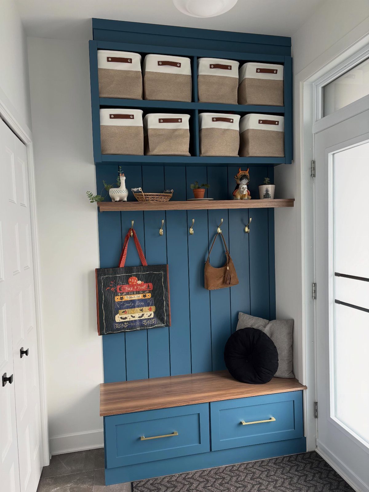 Blue built-in mudroom bench with wooden seat, storage drawers, and upper cubby bins.
