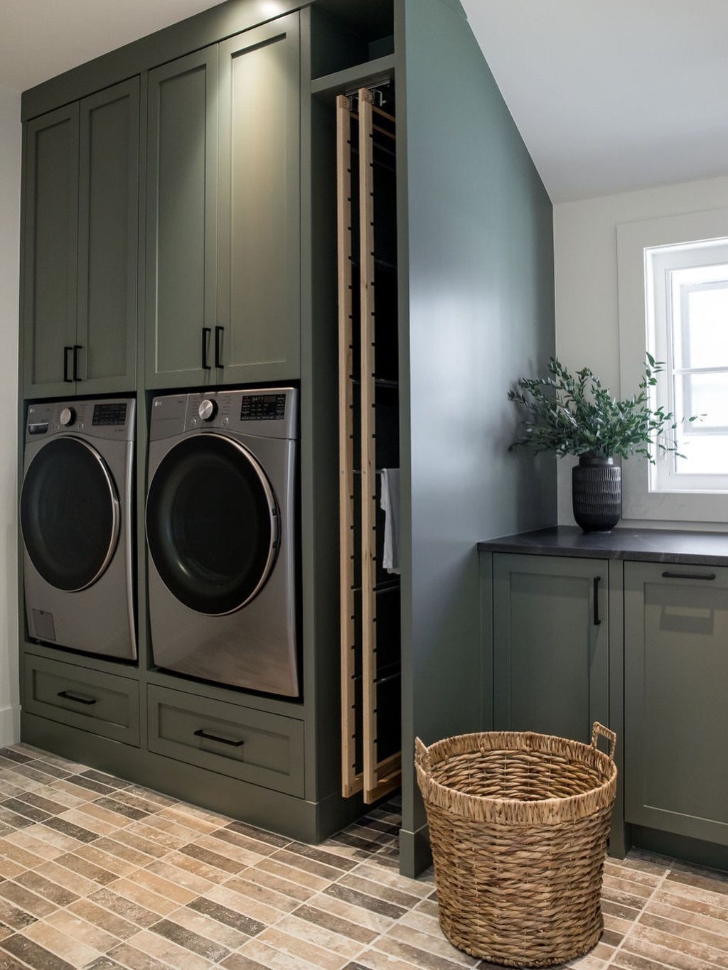 Pull-out wooden drying rack integrated into sage green laundry room cabinetry.