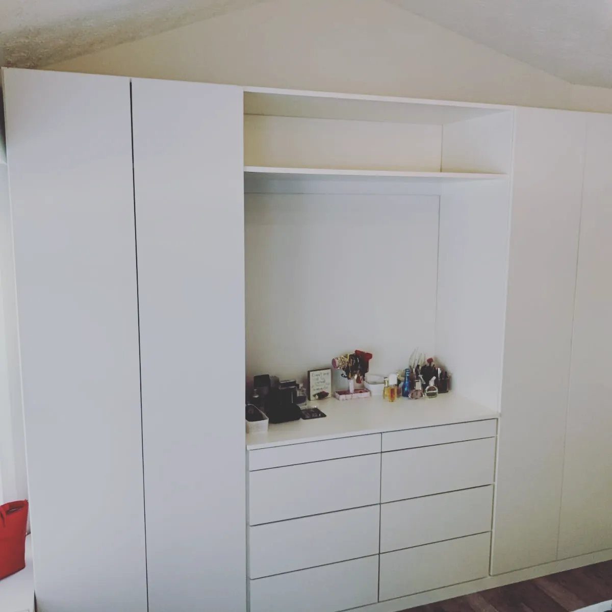 White built-in wardrobe with integrated vanity area and storage drawers in a bedroom.