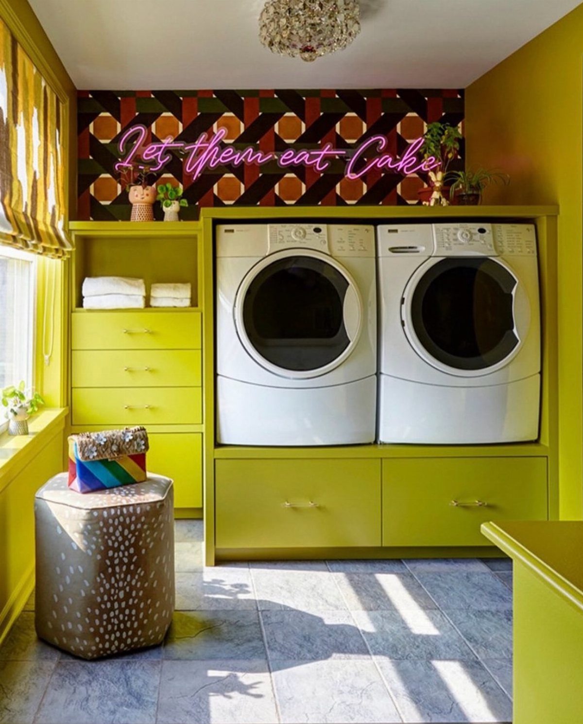 Bright yellow laundry room with white machines and a pink neon sign.