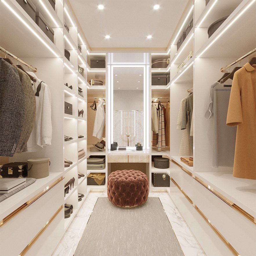 Luxury walk-in closet featuring a built-in vanity area with a velvet ottoman.