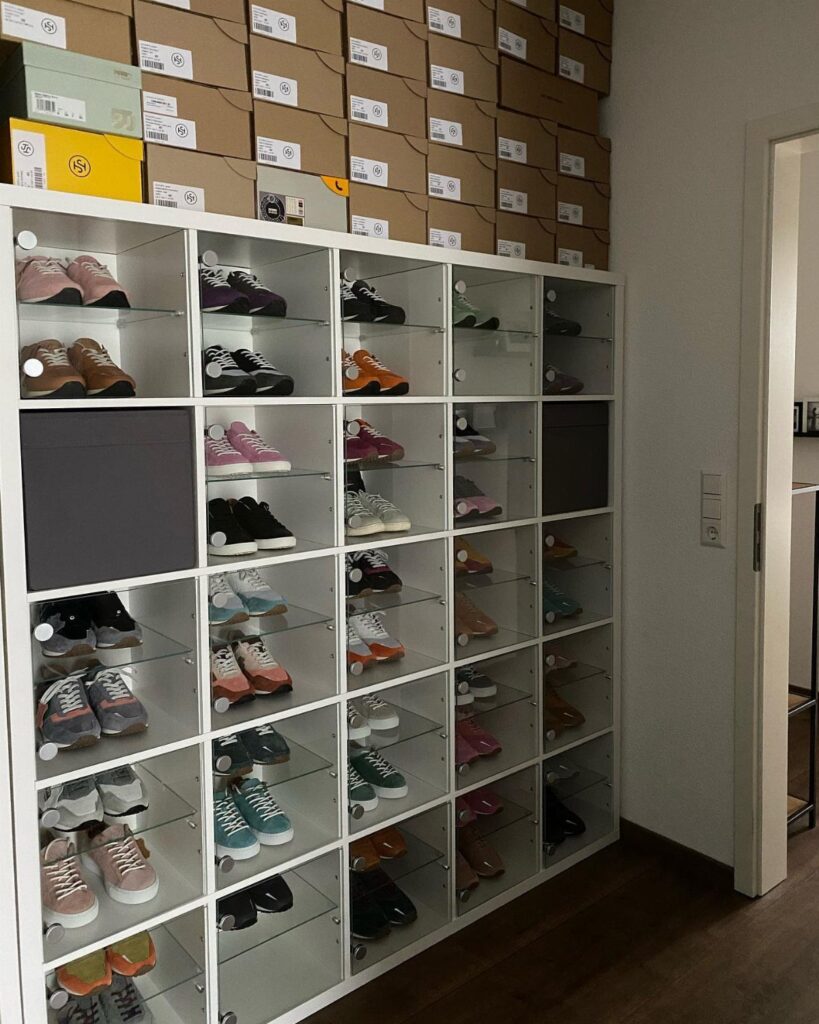 White KALLAX shelving unit used as a shoe cubby for a large collection.