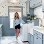 Woman standing in a blue laundry room with a drum-shaped ceiling light fixture.