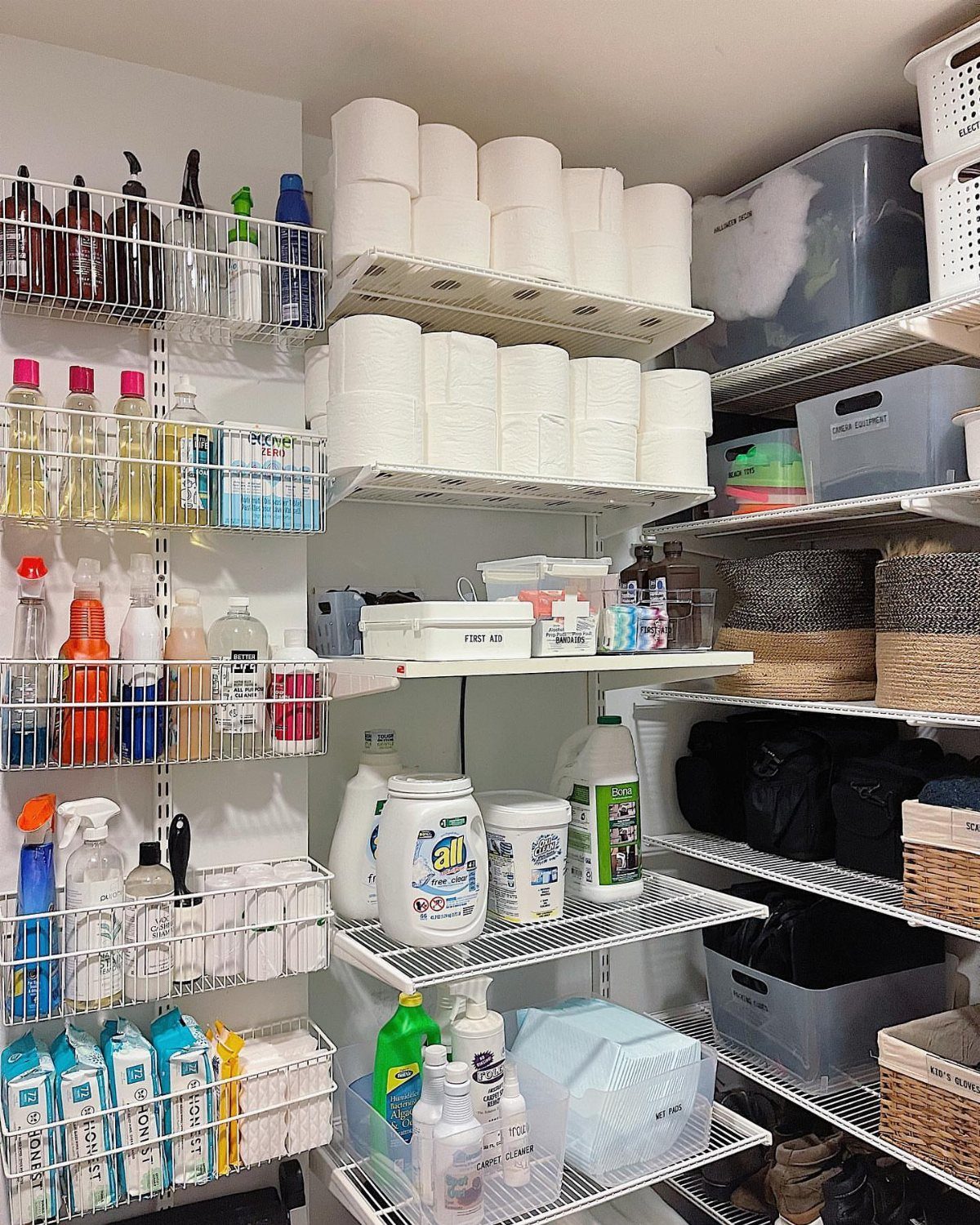 White wall-mounted closet system with wire baskets and shelves holding laundry supplies.