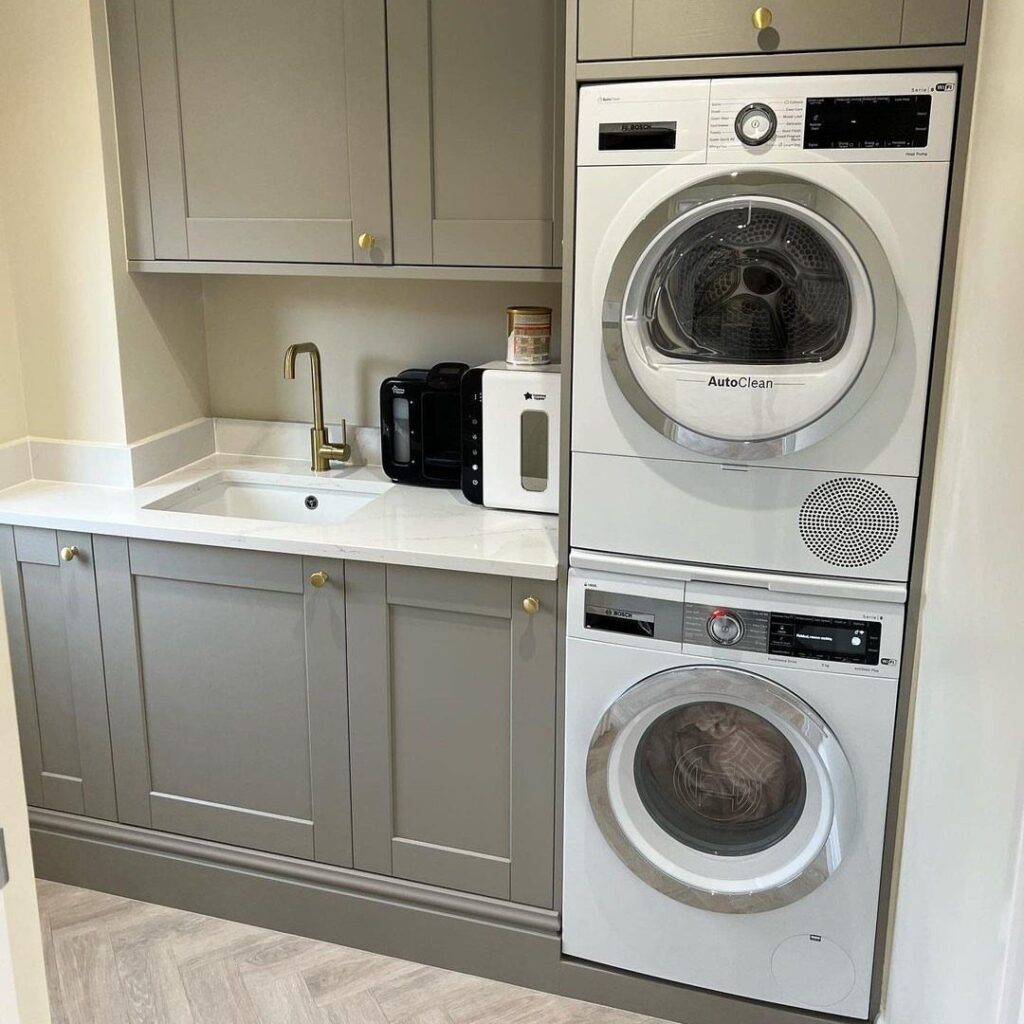 Laundry utility room with grey cabinets, white countertop, and stacked washer and dryer.