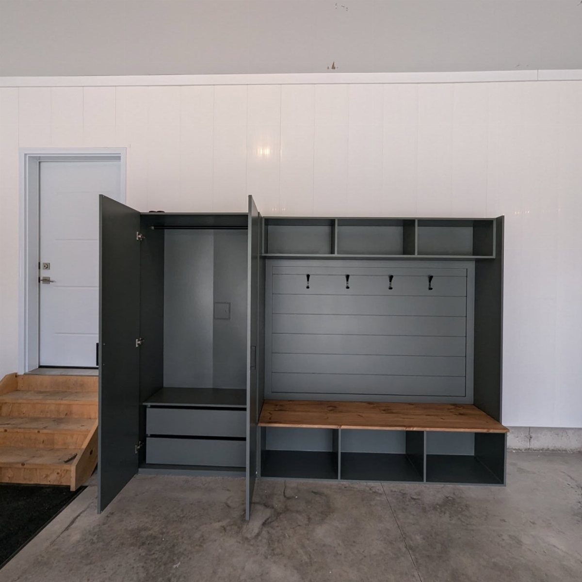 Grey mudroom storage unit with wooden bench and lockers in a white garage