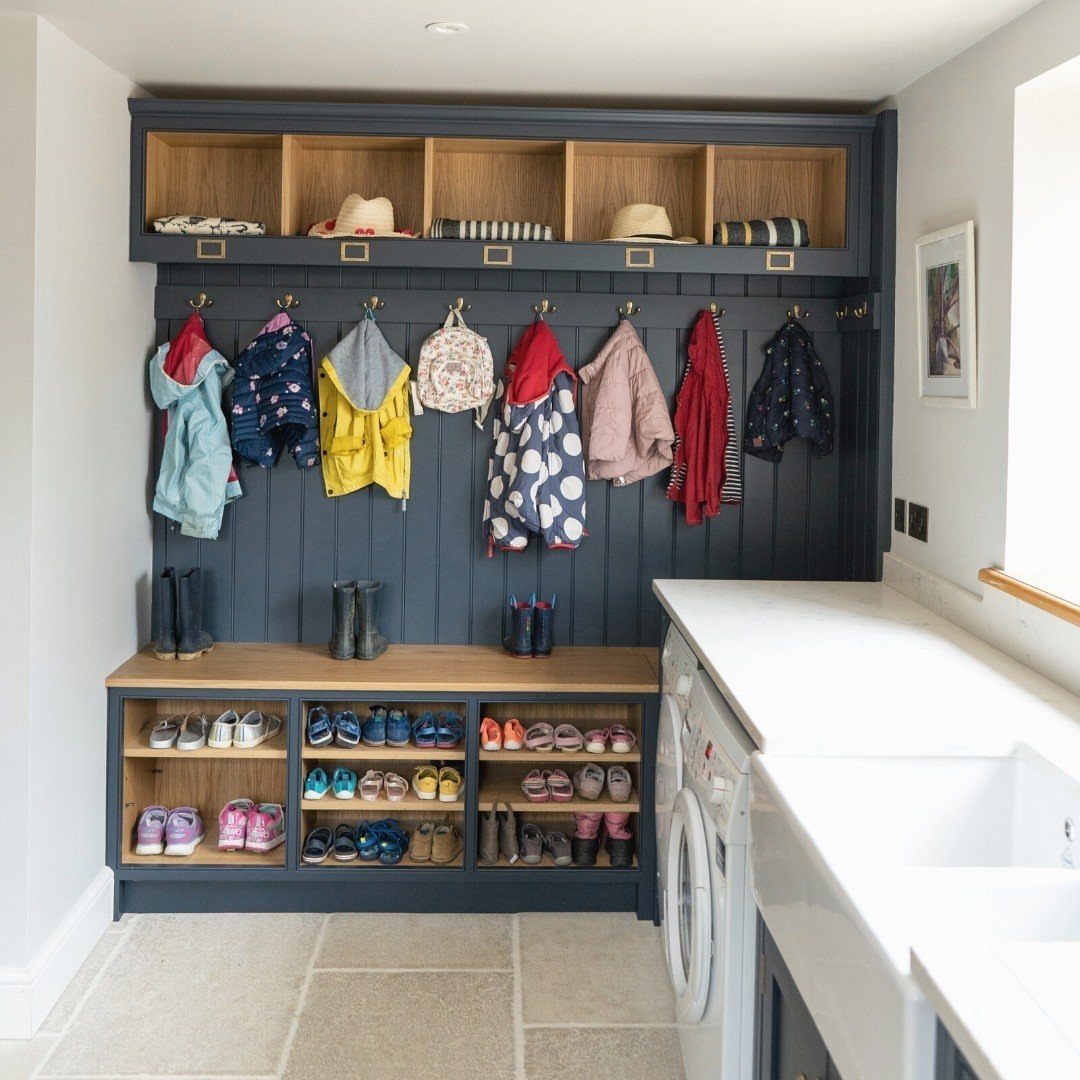 Children's coats and bags hanging from hooks in a blue built-in mudroom unit.