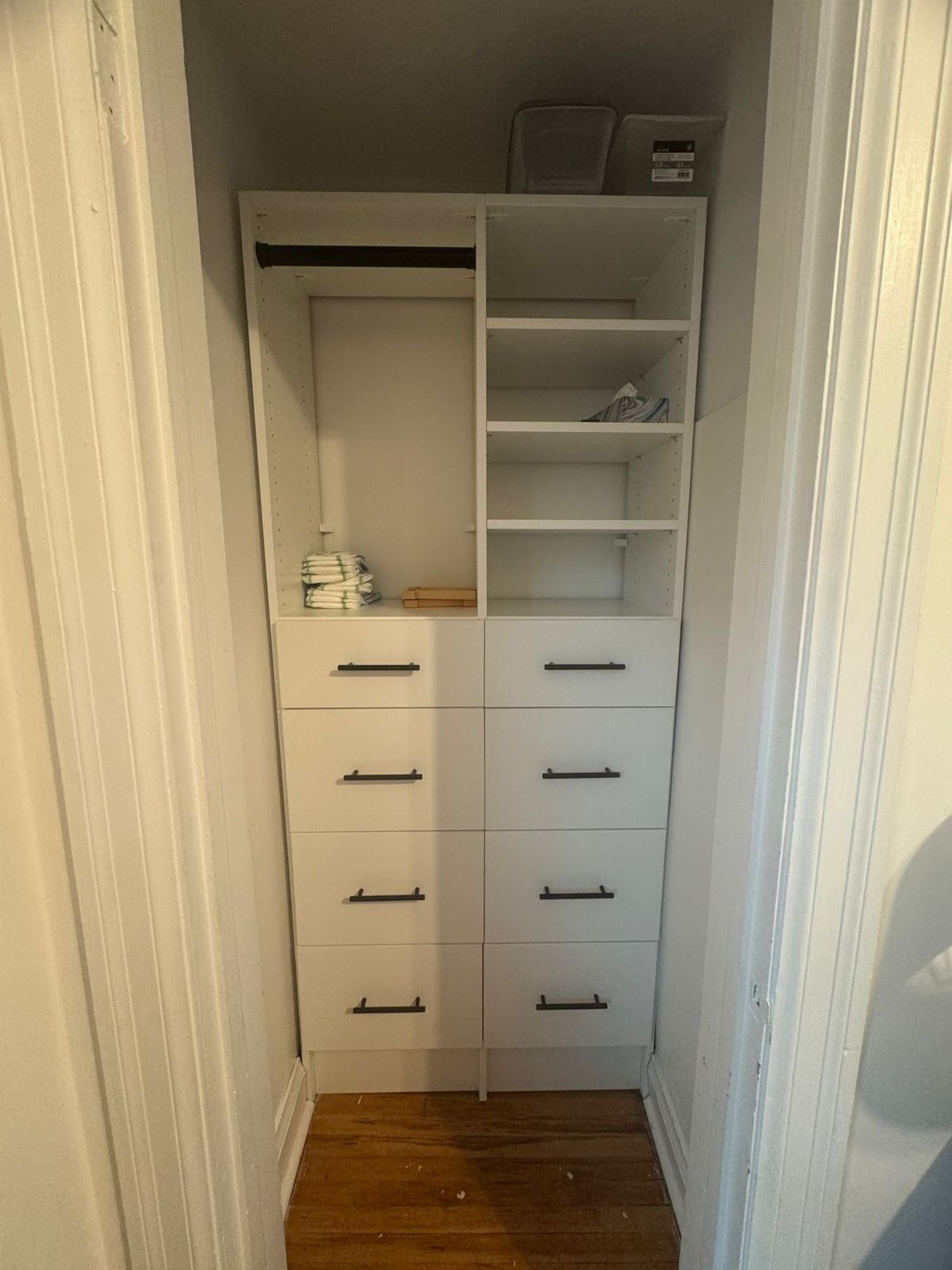 White storage unit with drawers and shelves inside a small narrow closet