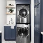 Navy blue cabinets and stacked silver washer dryer in a modern laundry room.