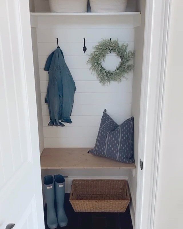 Converted closet mudroom with a wooden bench, blue rain boots, and wall hooks.