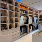 Large walk-in closet with integrated lighting, open shelving, and a central storage island.