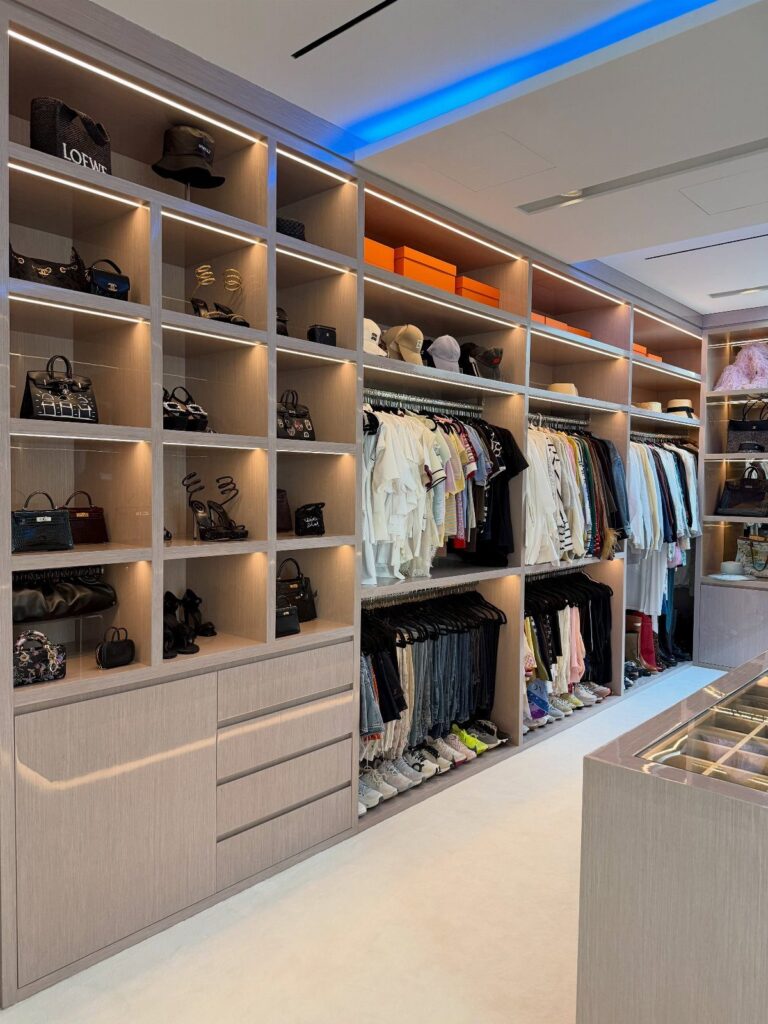 Large walk-in closet with integrated lighting, open shelving, and a central storage island.