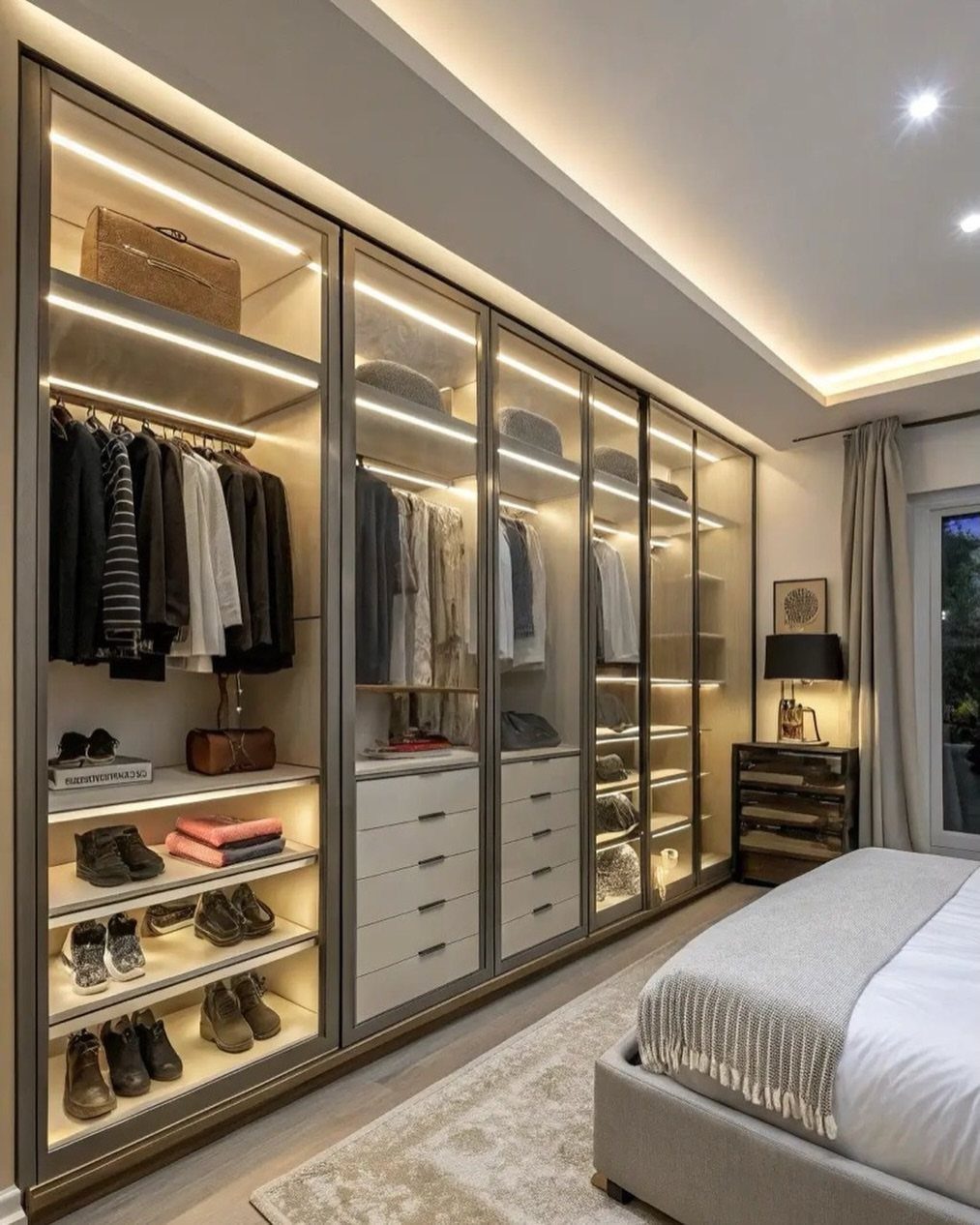 Modern built-in wardrobe with glass doors and integrated warm LED strip lighting.