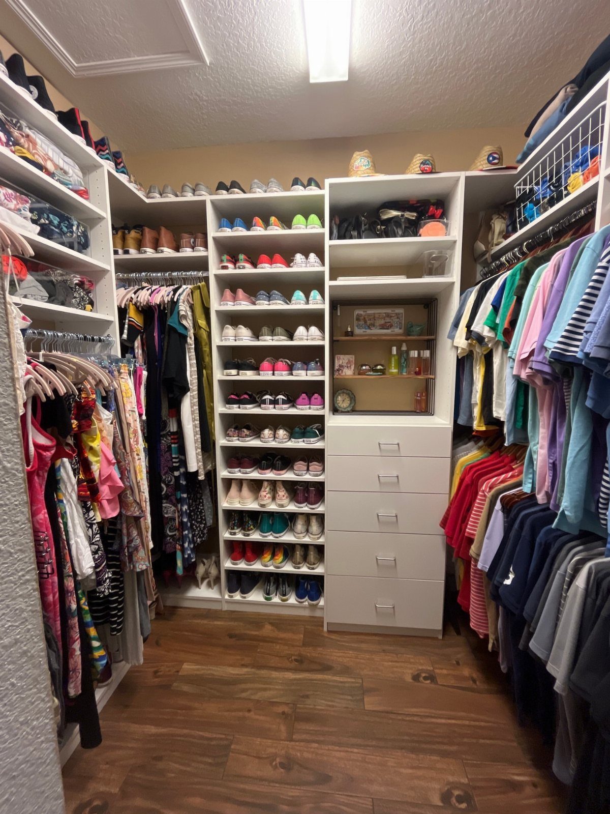 White walk-in closet with dedicated zones for hanging clothes, shoes, and folded items.