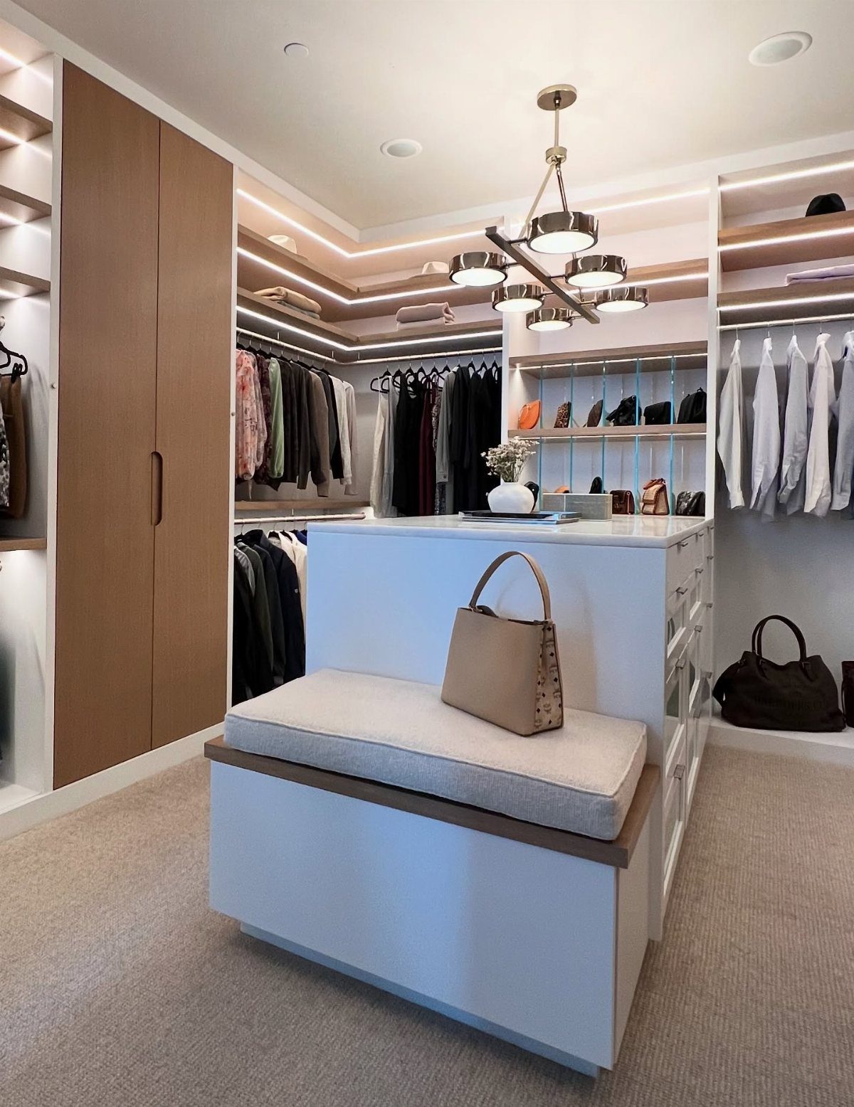Walk-in closet with a white central island featuring a cushioned seating area.