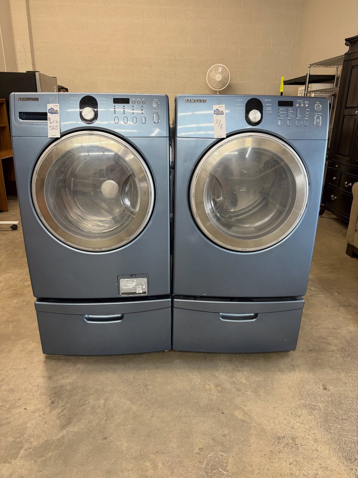 Blue Samsung washer and dryer set elevated on pedestals with pull-out drawers.